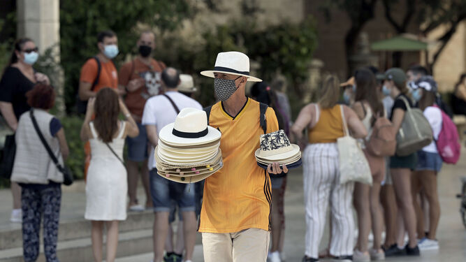 Un hombre vende sombreros para aliviar el calor a turistas en Valencia.