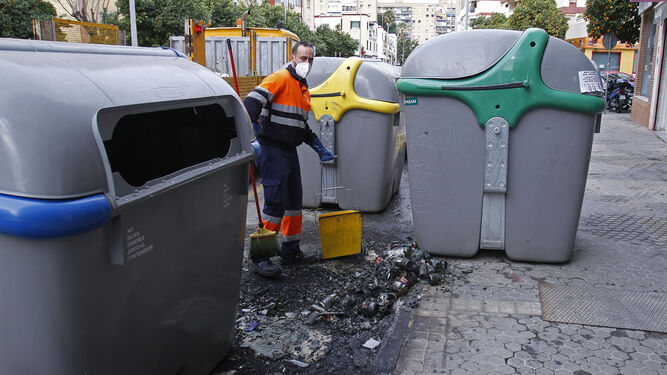 Un empleado de Lipasam recoge restos junto a contenedores de residuos en una calle de la ciudad.