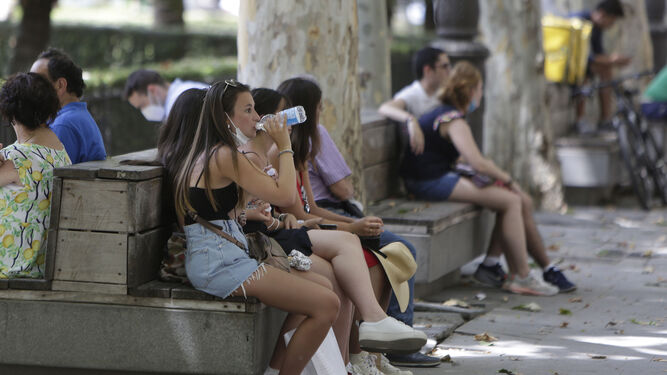 Varias personas se protegen de las altas temperaturas a la sombra en una céntrica plaza de la capital.