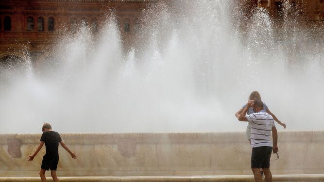 Varias personas se refrescan en la fuente de la Plaza de España