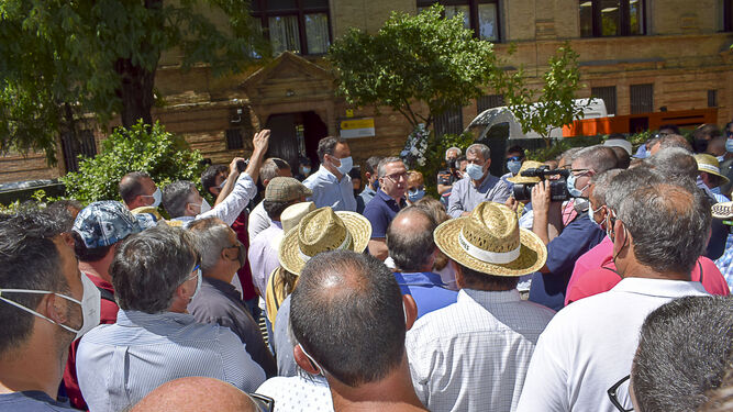 Un momento de la protesta de los agricultores ante la sede de la CHG de Sevilla y, al fondo, el alcalde de Los Palacios.