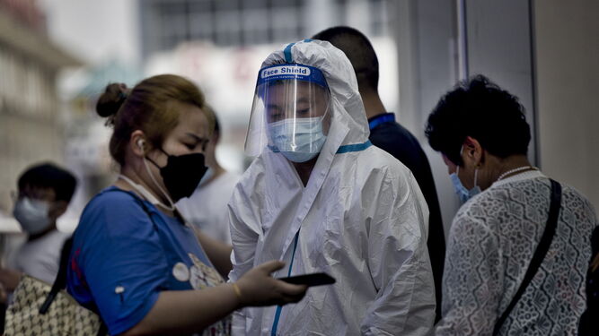 Una mujer enseña su certificado de vacuna a un sanitario en un control en una estación de Pekín