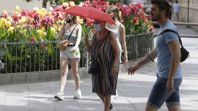 Una mujer se protege del sol con un paraguas.
