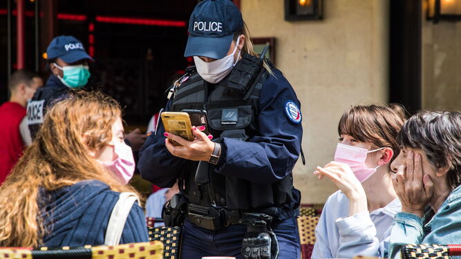 Un policía francés comprueba un 'pase sanitario' en el móvil del cliente de un bar.