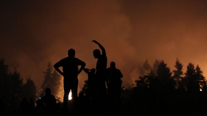 Voluntarios luchan contra el fuego y esperan apoyo durante un incendio forestal cerca del pueblo de Kamatriades en la isla de Eubea.