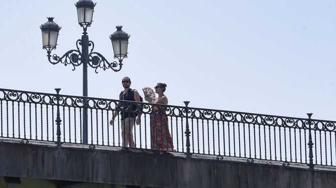 Un pareja pasea por el Puente de Triana.