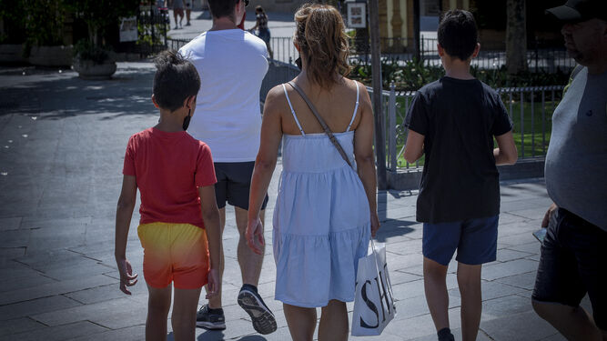 Una mujer camino junto a dos menores por una céntrica calle de la ciudad de Sevilla.