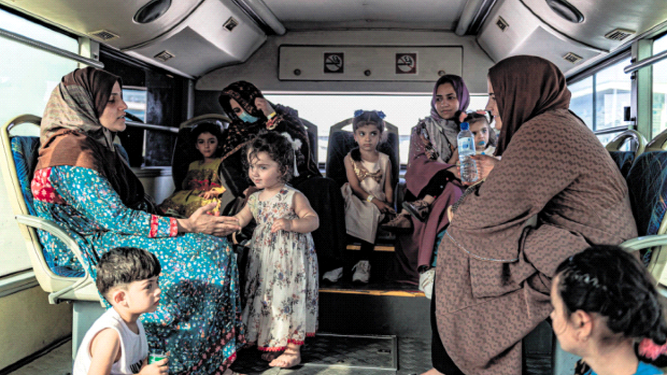 Mujeres afganas y sus hijos son trasladados al avión que las sacará de Kabul.