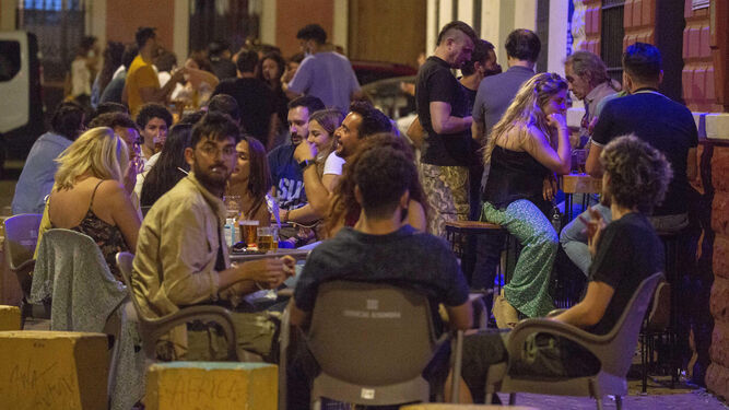 Un grupo de jóvenes consume en el exterior de un bar en Sevilla.