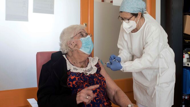 Una sanitaria inocula la vacuna  a una usuaria de una residencia geriátrica.