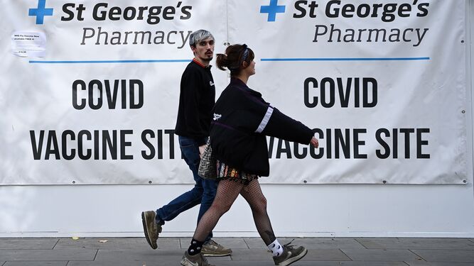 Dos jóvenes pasan caminando ante un centro de vacunación, ayer en Londres.