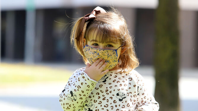 Una niña pequeña utilizando una mascarilla de tela reutilizable.