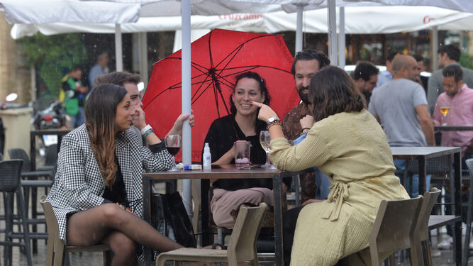 Gente con paraguas en una terraza.