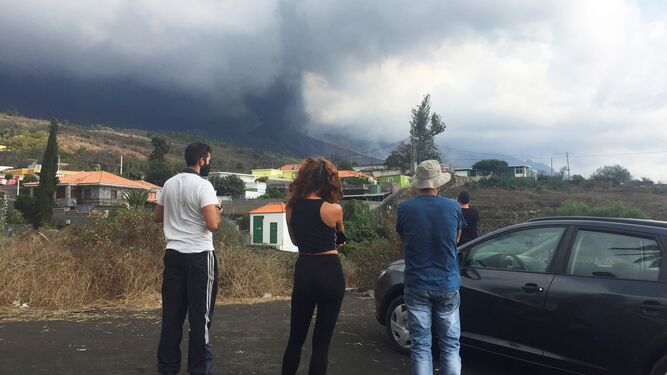 Varios vecinos desalojados contemplan en el barrio de Tijuya en El Paso, las evoluciones bajo una gran nube de ceniza del volcán  en Cumbre Vieja.