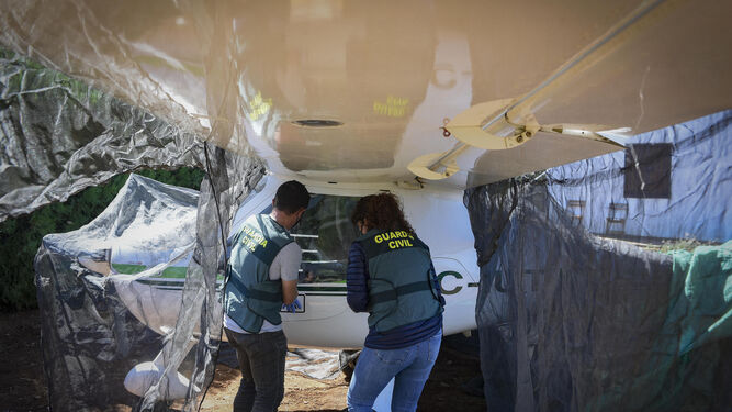 Dos agentes de la Guardia Civil muestran la avioneta incautada en Carmona.