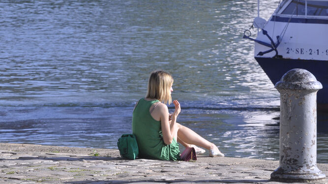 Una joven disfruta del sol junto al río.