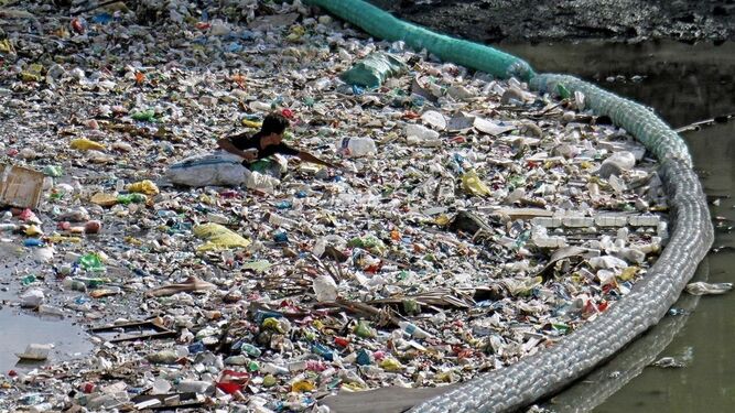 Un hombre nada en un mar de residuos plásticos.