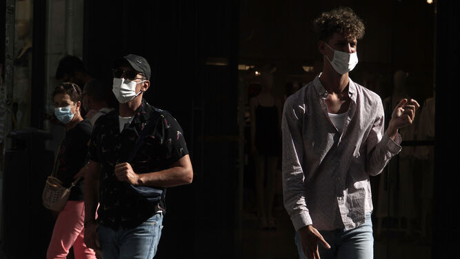 Tres personas con mascarillas en una calle de Sevilla.