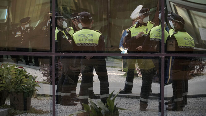 Policías locales de Sevilla, reflejados en un cristal de la Jefatura, durante los actos de San Clemente de 2020.