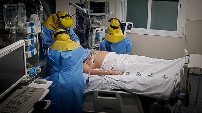 Sanitarios atienden a un enfermo Covid en un box de la UCI del hospital de Valme.