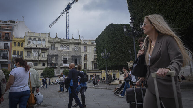Turistas pasean por la Plaza de San Francisco, con grúas al fondo del proyecto de un nuevo hotel.