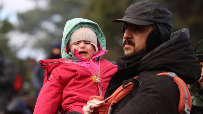 Un migrante sostiene a un bebé en la frontera entre Bielorrusia y Polonia.