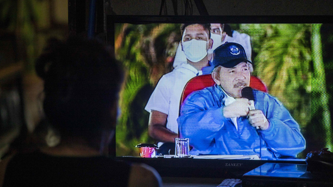 Una mujer observa en el televisor al presidente de Nicaragua, Daniel Ortega.