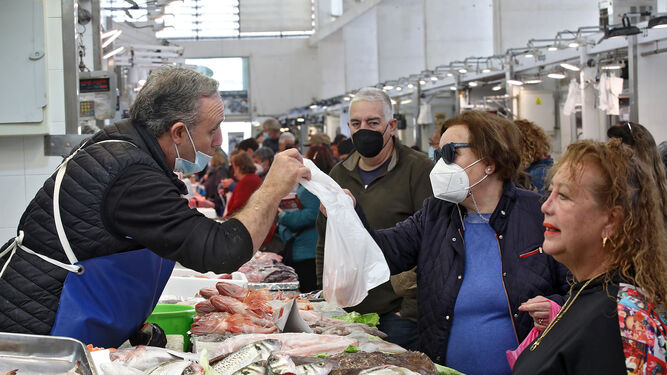 Un pescadero del Mercado Central de Cádiz entrega una compra a una clienta.