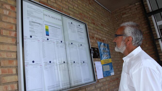 Un hombre revisa las listas de escolarización en un centro educativo andaluz.