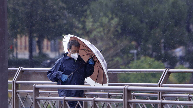 Un hombre se protege de la lluvia con un paraguas.