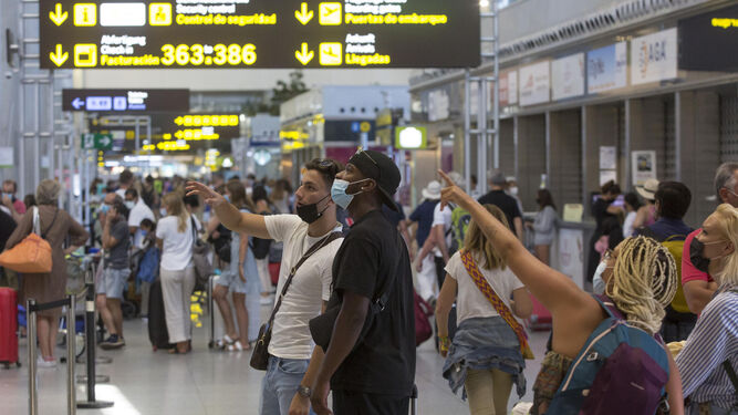 Numerosos viajeros miran los paneles que hay en los aeropuertos