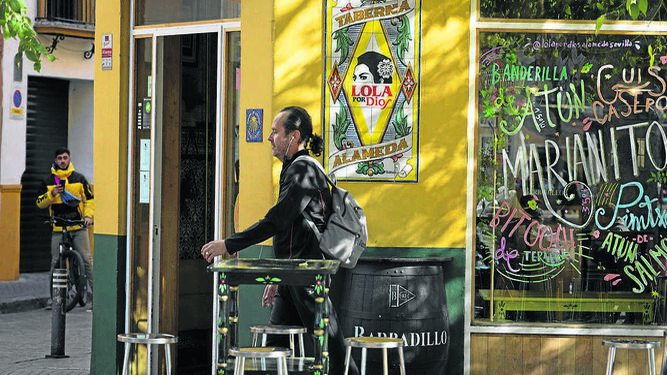 Un hombre pasa delante del cartel de la taberna Lola por Dios, en la Alameda de Hércules.