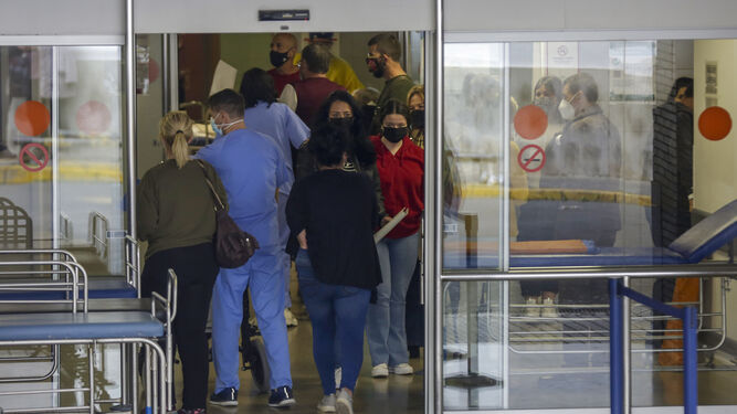 Personal sanitario entre un grupo de usuarios en uno de los accesos al Hospital Virgen del Rocío.