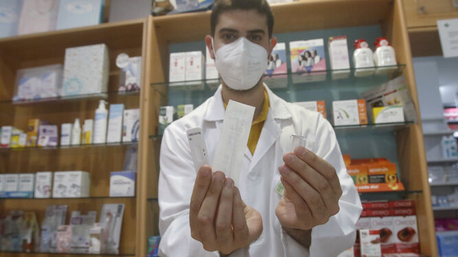 Un farmacéutico muestra un test de antígenos de venta en farmacias.