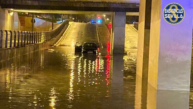 Un coche atrapado en el paso subterráneo de la calle Alfonso Lasso de la Vega, por acumulación de agua de lluvias.