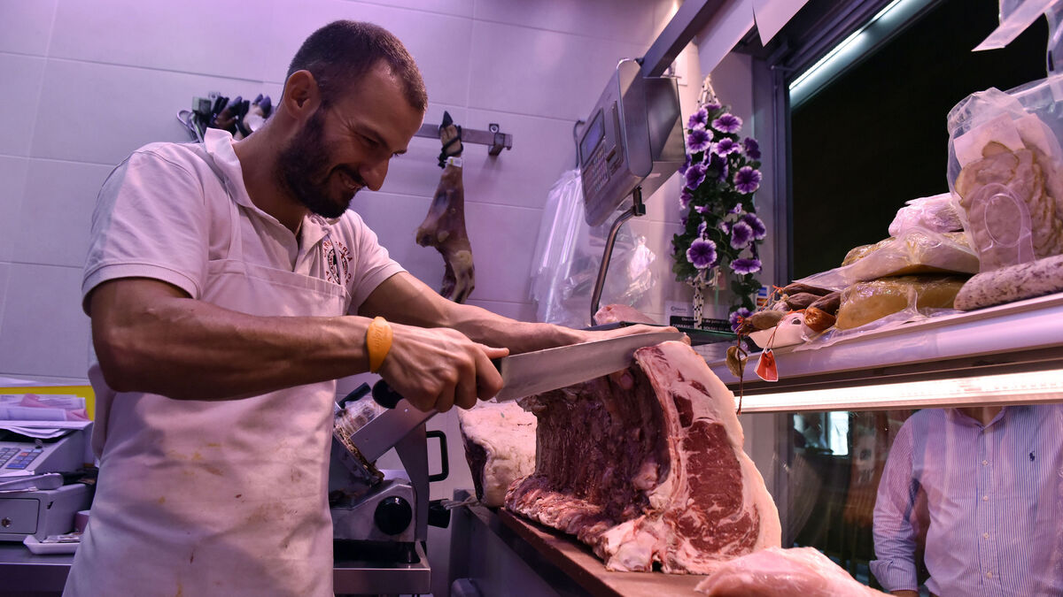 Un carnicero cortando carne en un mercado de la ciudad.