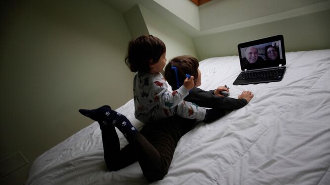 Dos niños conversan con sus abuelos mediante una videollamada.