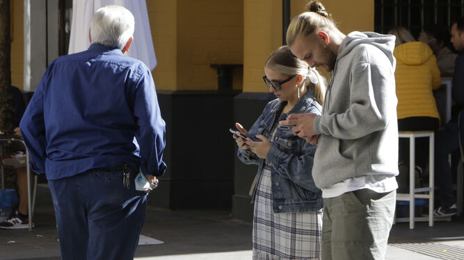 Una pareja de turistas consulta su teléfono móvil