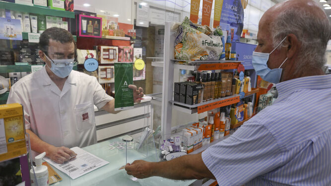 Un farmacéutico atiende a un usuario en una botica de Málaga.