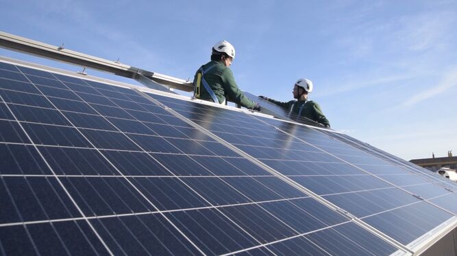 Dos operarios instalan una placa fotovoltaica.