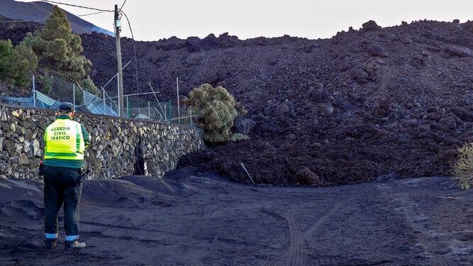 Un agente de la Guardia  Civil  contempla una de las colada del volcán  de La Palma