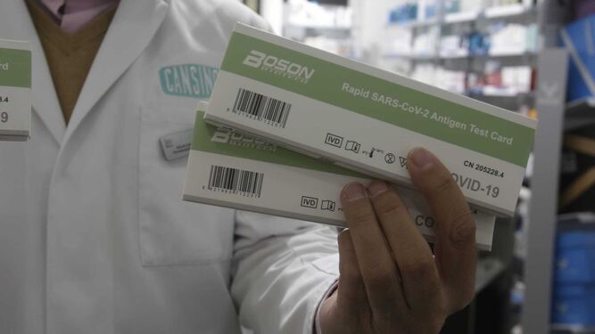 El farmacéutico sevillano Julio Cansino muestras dos ejemplares de test de antígenos a la venta.