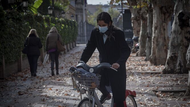 Un hombre pasea con su bicicleta por el centro de Sevilla.