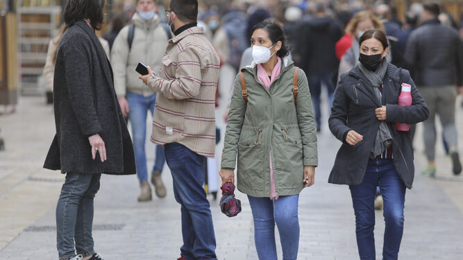 Varias personas caminando con mascarilla en una calle del centro de Málaga