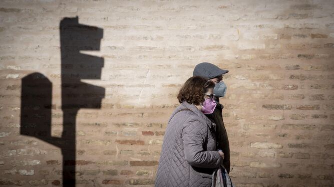 Dos personas caminan por el centro de Sevilla, protegidas con mascarillas.