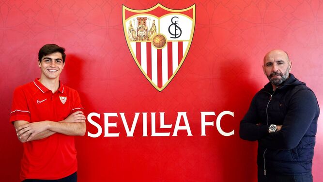 Juanlu posa ante el escudo del Sevilla junto a Monchi.