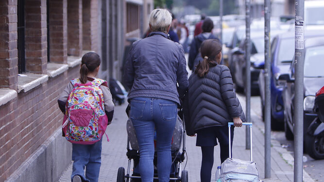 Una mujer camino del colegio con dos menores en edad escolar.