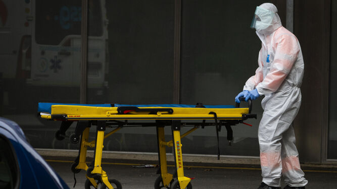 Personal sanitario  traslada una camilla a las puertas de un hospital.