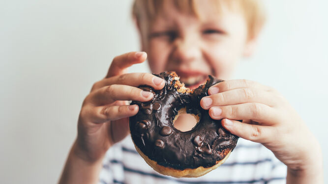 Un menor muestra un donut de chocolate.