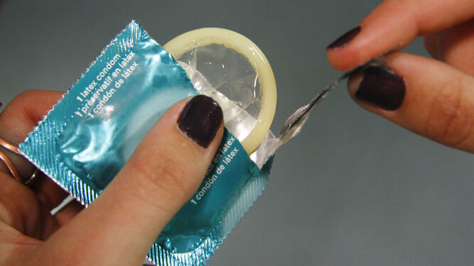 Una farmacéutica muestra la apertura del envase de un preservativo.